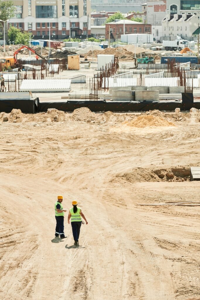 Overhead drone shot of a construction site with two workers in safety gear.